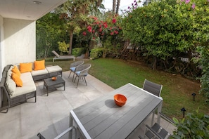 An outdoor patio with a sofa set, chairs, and a dining table. - Private Garden Duplex in Voula by GHH (Voula)
