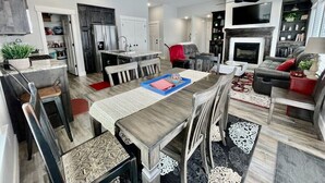 A modern kitchen with a dining area, a fireplace, and a living room with a sofa and TV. - Hazen Home. Family Retreat. Fully equipped home. 2 min to shopping and parks. (Ammon)