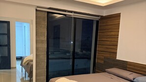 A modern bedroom with a large bed, a sliding glass door leading to a balcony, and a wooden headboard.