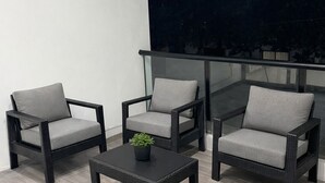 A balcony with wicker furniture, a small table, and a potted plant.