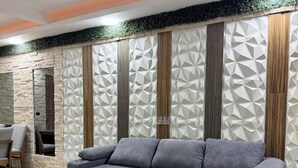 A modern living room with a grey sectional sofa, a stone accent wall, and a geometric patterned wall.