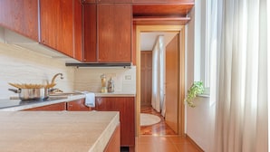Cozinha com armários de madeira, bancada e janela com cortinas.