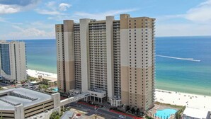 Un hotel di grattacielo con diverse altezze, vista sulla spiaggia e una piscina.