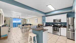 Una cucina moderna con isola centrale, mobili bianchi, elettrodomestici in acciaio inossidabile e vista all'esterno.
