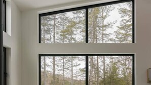 Una sala de estar moderna con un ventanal grande, un sofá, una mesa de centro y una chimenea.