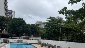 A rooftop swimming pool with stone tiles and lounge chairs. - Apto com Piscina e Sauna Perto da Praia da Barra (Rio de Janeiro)