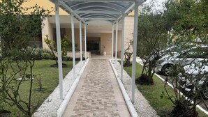 A covered walkway with a tiled floor, leading to a building entrance. - Apto com Piscina e Sauna Perto da Praia da Barra (Rio de Janeiro)