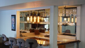 A bar area with multiple stools, shelves with glassware, and a mirror reflecting the space. - Lakebreeze Retreat (tweed)