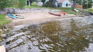 A riverside view with kayaks and canoes on a sandy shore, surrounded by residential houses and greenery. - Lakebreeze Retreat (tweed)