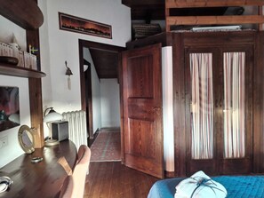 A room with a wooden door, a bed with a blue quilt, a radiator, and a framed picture on the wall. - Singing in the Wind - Kite Villa Stagnone (Marsala)