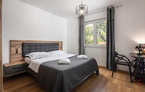 Une chambre bien rangée, avec un lit, des tables de chevet, un bureau et une chaise.
