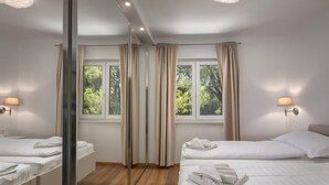 A hotel room with two beds, a large mirror, and windows with curtains. - Awesome home in Pula with private swimming pool, can be inside or outside (Pula)