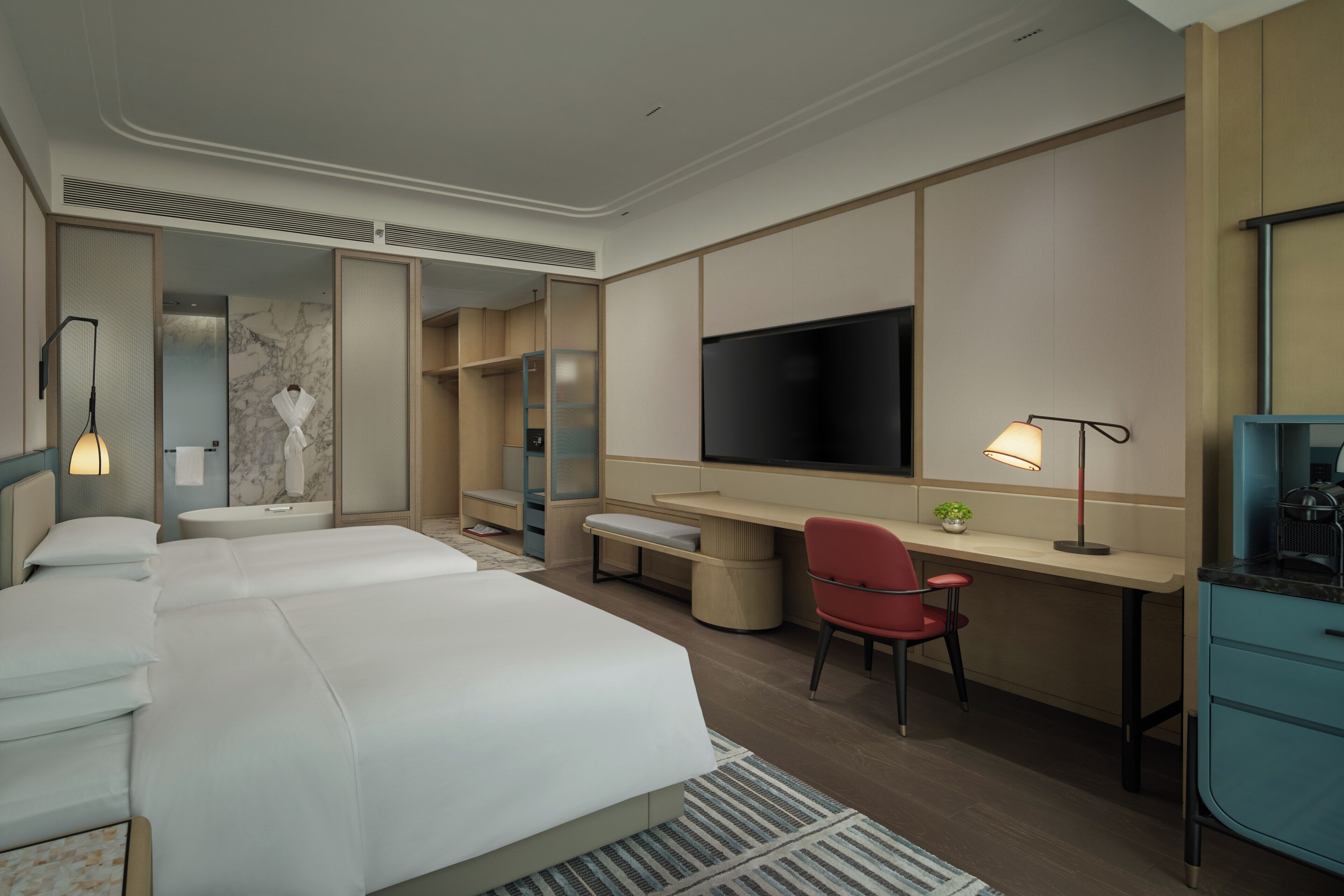 Ein Hotelzimmer mit einem großen Bett, einem Schreibtisch, einem Fernseher und einem Sessel.