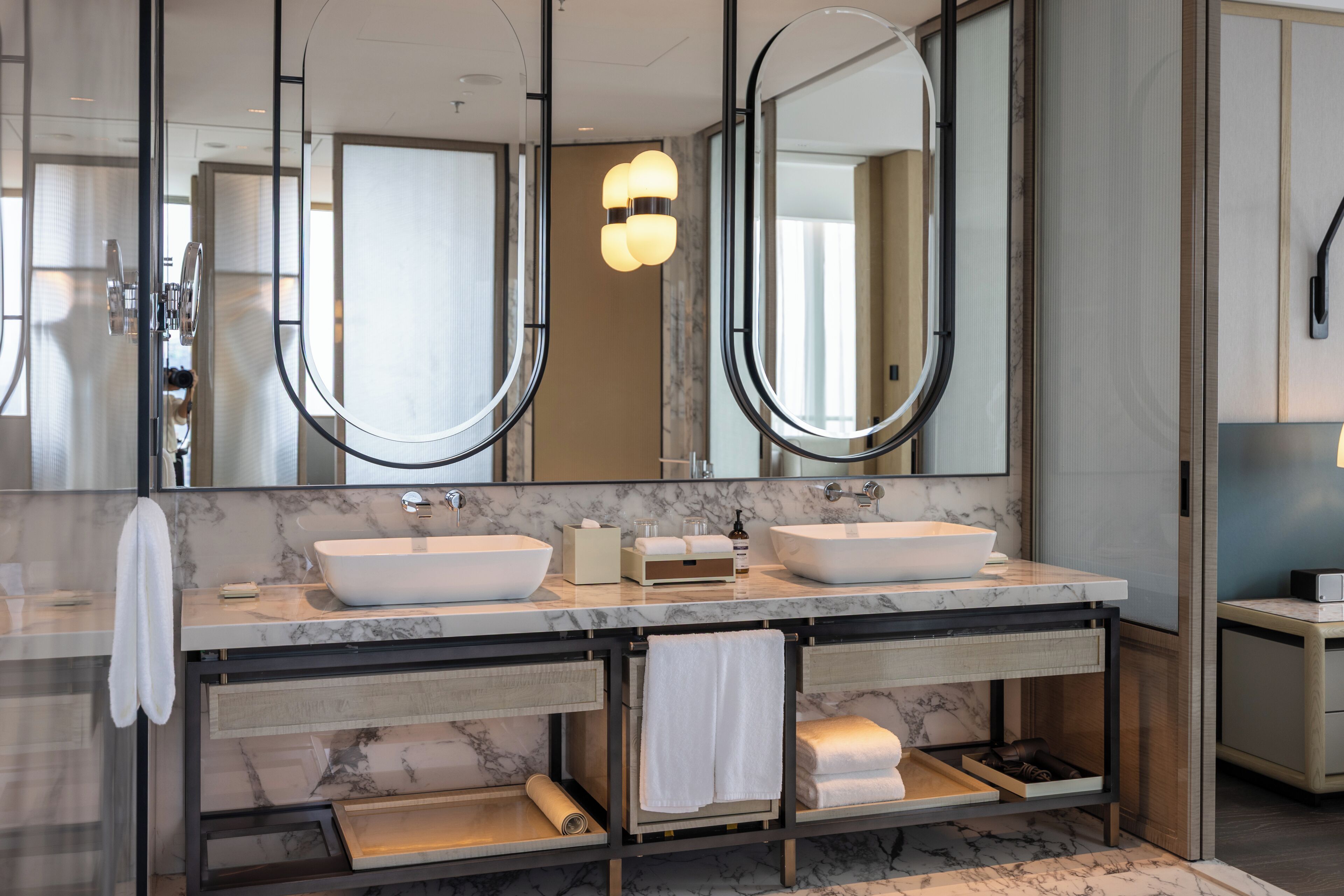 A modern bathroom with two sinks, a large mirror, and a towel rack.