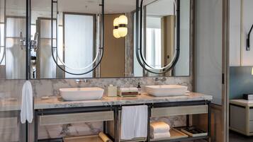 A modern bathroom with two sinks, a large mirror, and a towel rack.