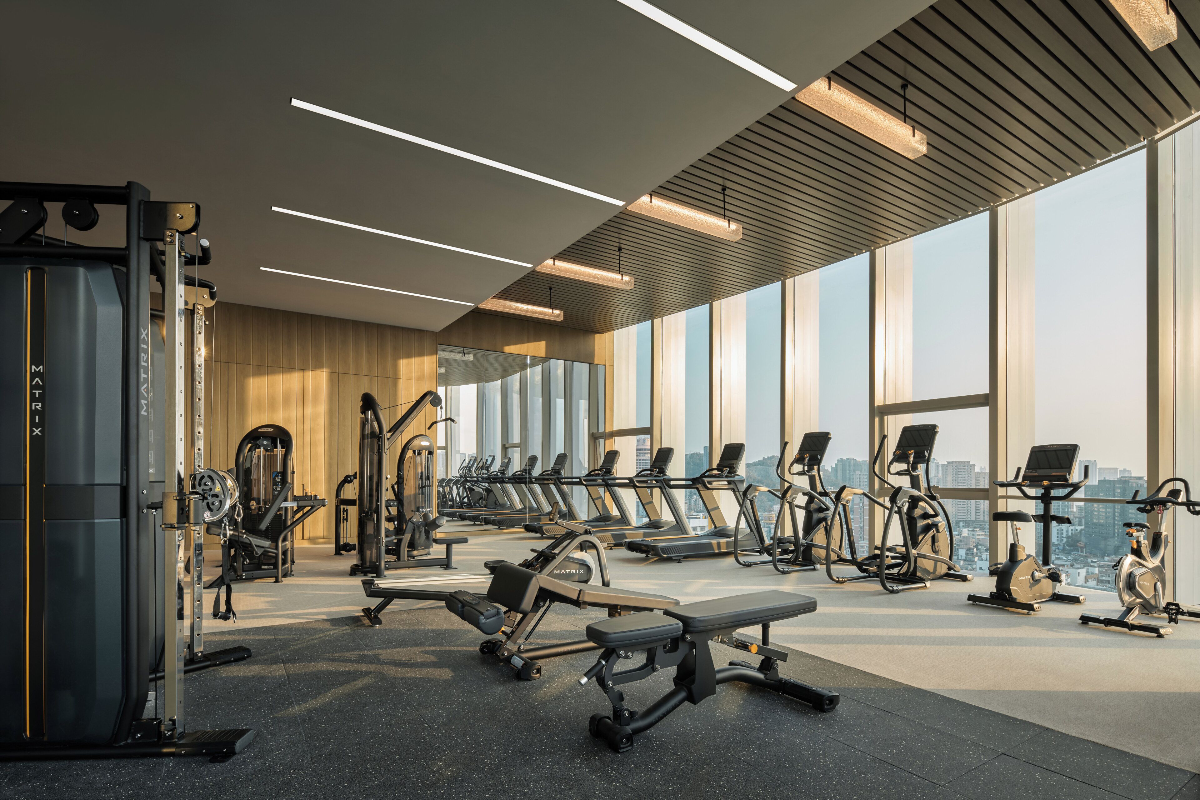 A modern gym with treadmills, elliptical machines, and weight equipment.