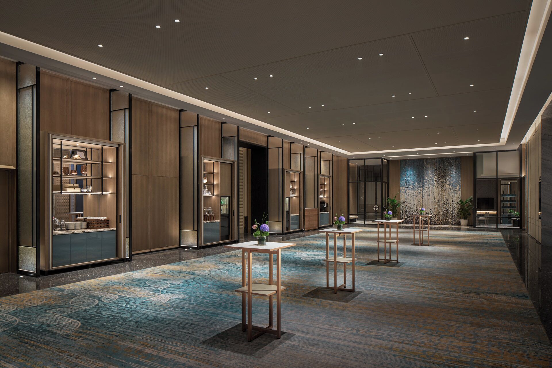 Een ruime hotellobby met een hoge plafond, ingebouwde verlichting en een kamerbreed tapijt met dessin.