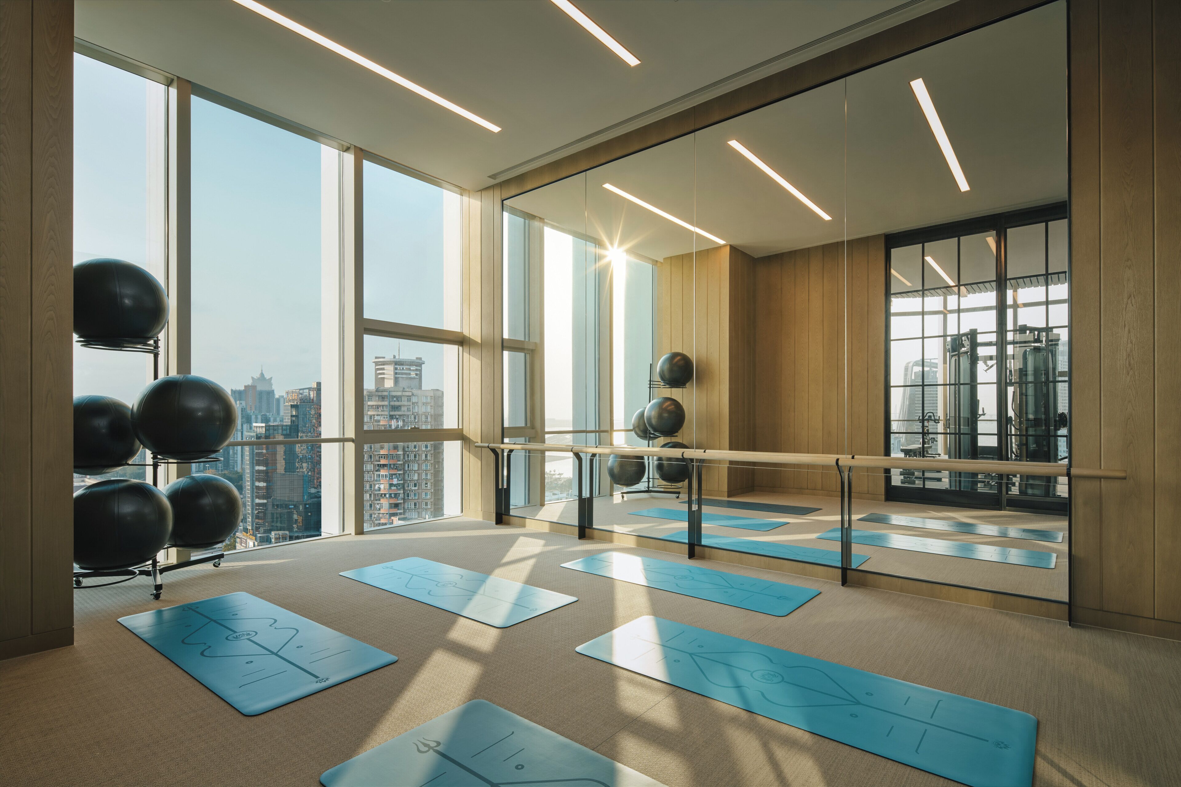 Um quarto amplo com grandes janelas, uma barra de balé e bolas de exercício.