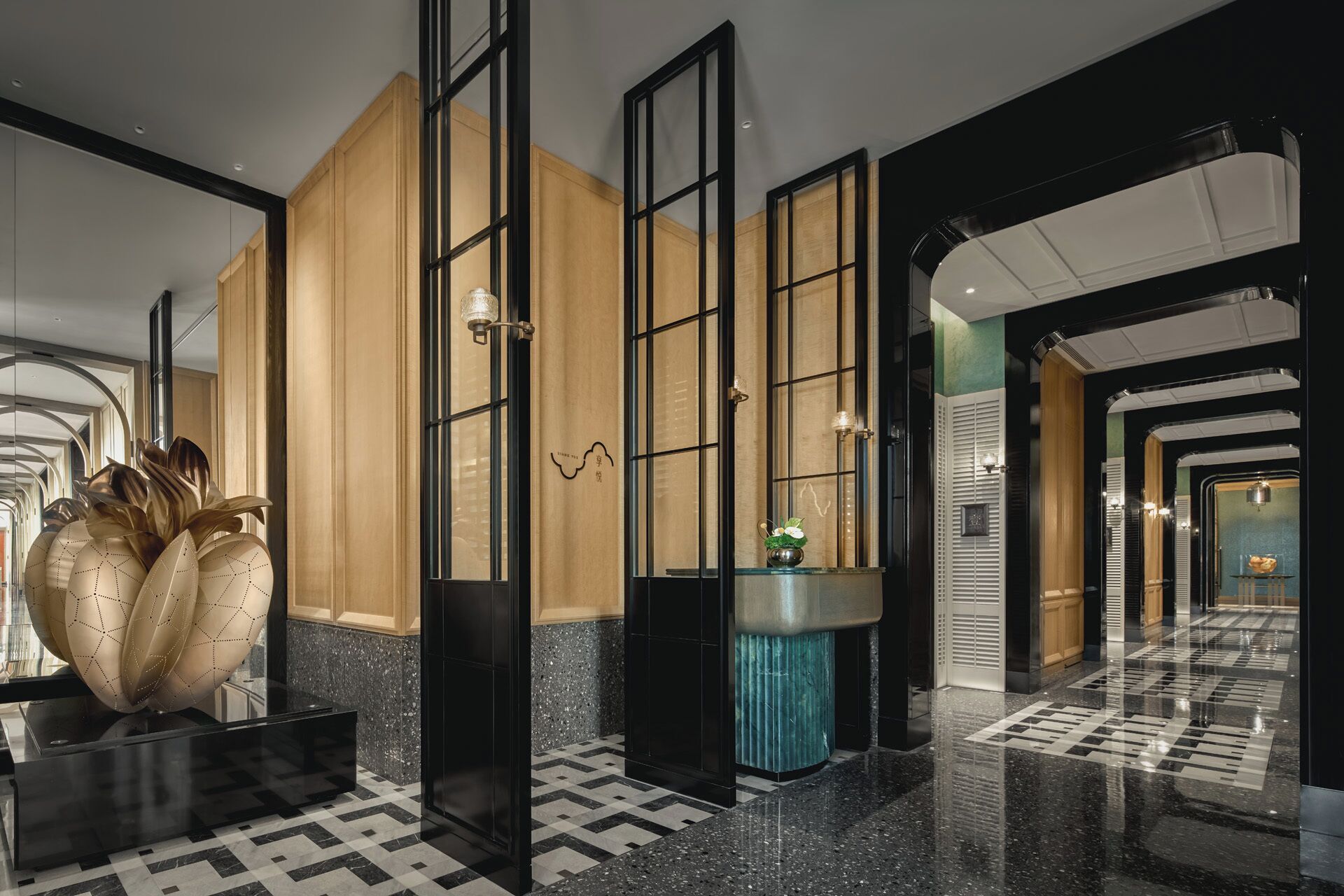 Un moderno vestíbulo de hotel con suelo a cuadros, un gran jarrón decorativo y un espejo que refleja el espacio.