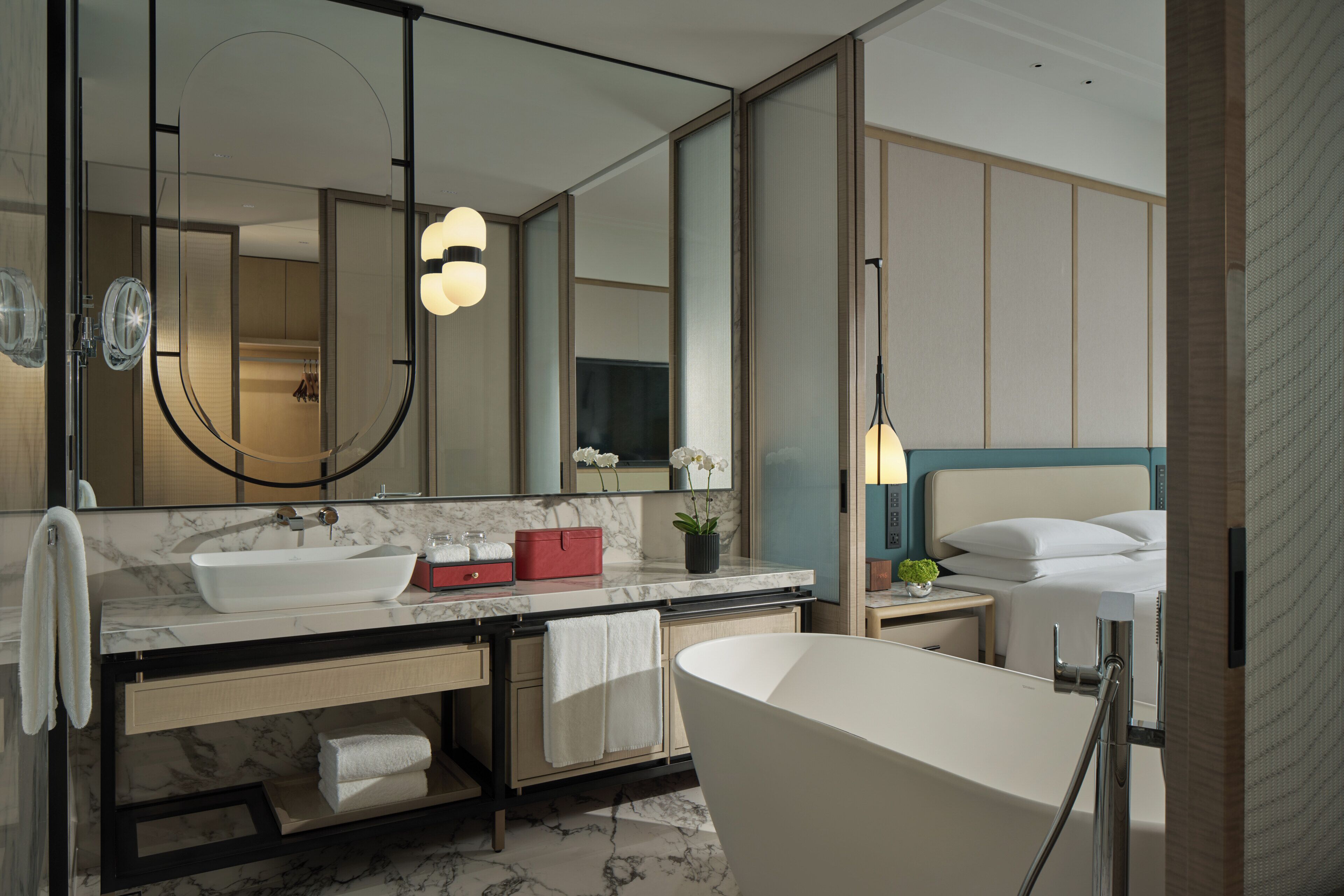 A modern bathroom with a large mirror, a sink, a bathtub, and a vanity with a towel rack.