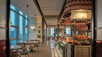 Un interior moderno con comedor, cocina y ventanas amplias que ofrecen vistas a la ciudad.