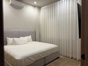 A bedroom with a bed, a headboard, an air conditioning unit, and a window with vertical blinds. - A pasos del Centro Historico, Bares, con Alberca (Mazatlán)