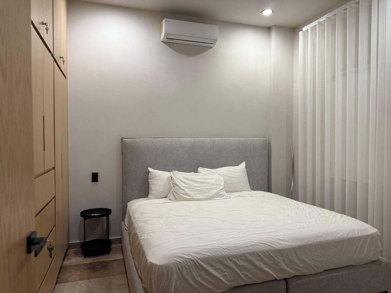 Une chambre à coucher comprenant un lit, une table de chevet, une armoire et un appareil de climatisation.
