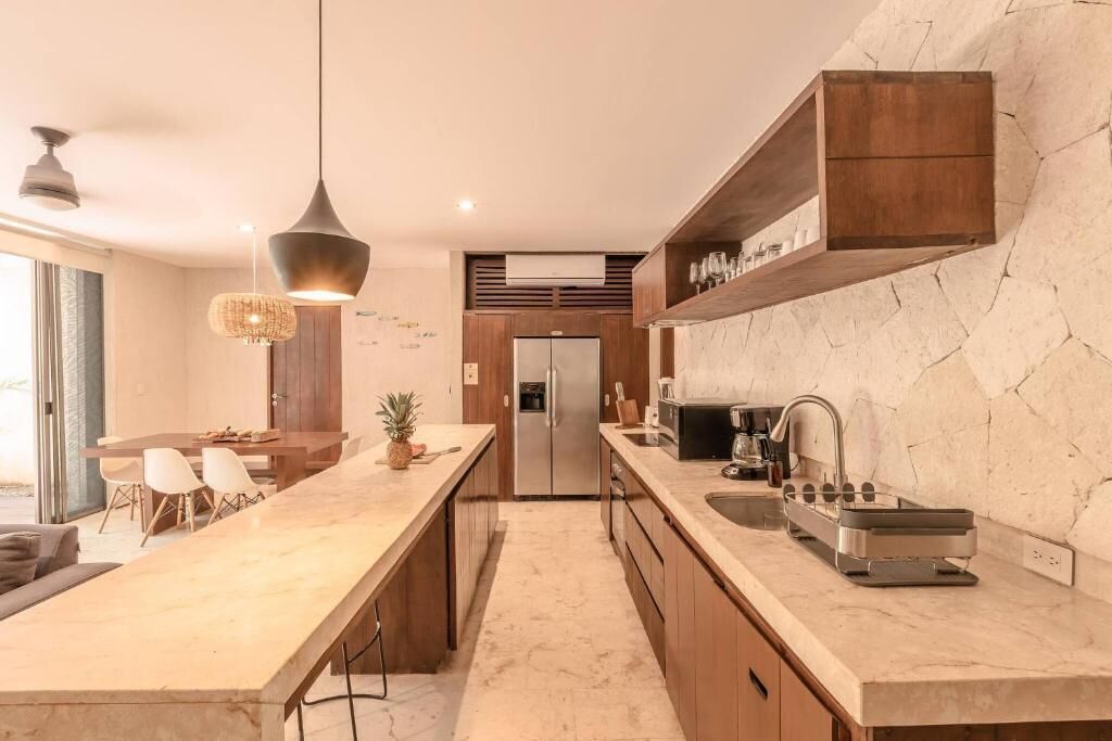 Una cocina moderna con encimera de mármol, armarios de madera y horno empotrado.