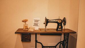 A vintage Singer sewing machine on a wooden table with a sign requesting low voice volume.