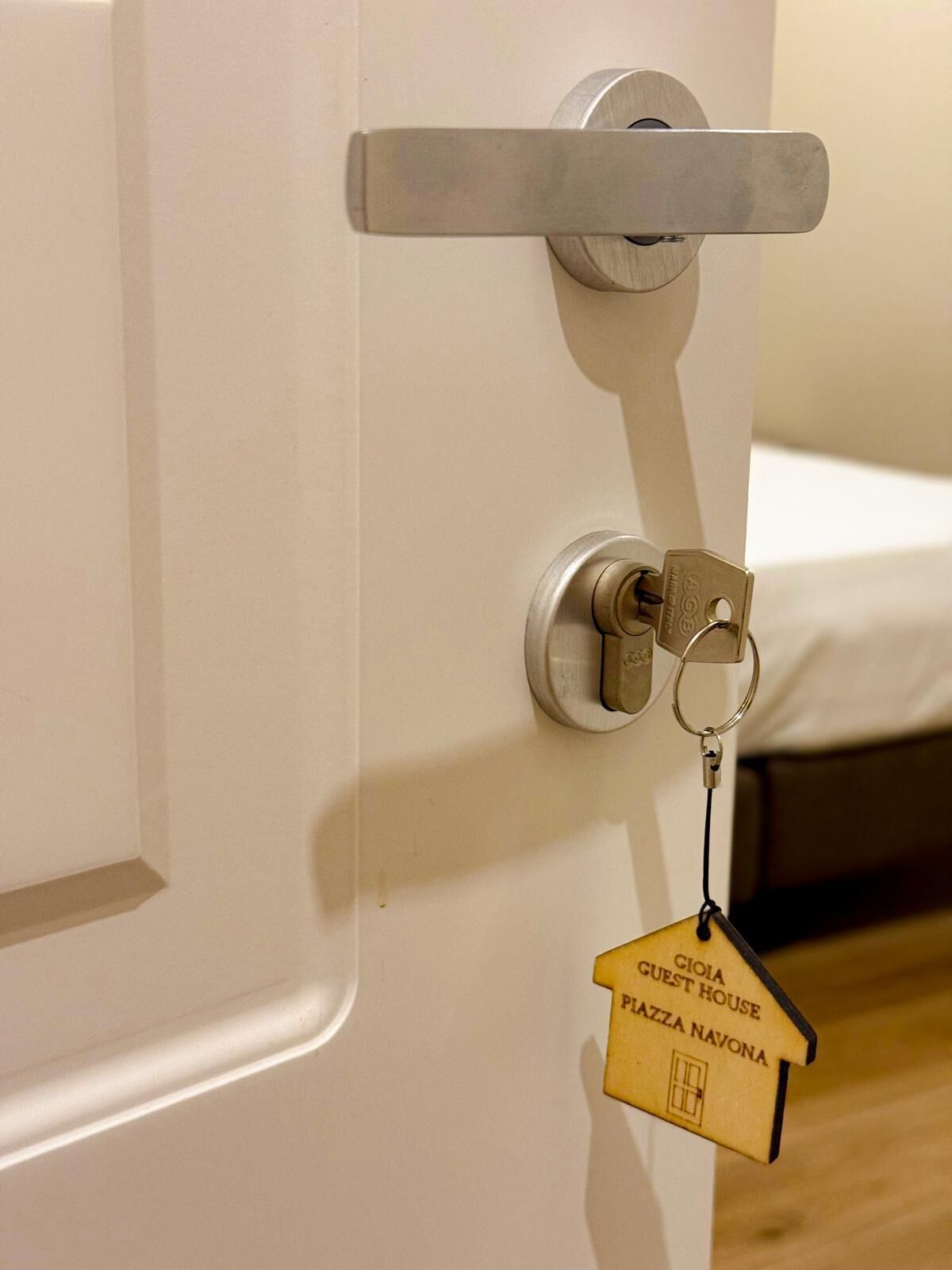 A door with a key lock and a keychain with a house-shaped keychain labeled "GIOIA GUEST HOUSE PIAZZA NAVONA".