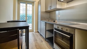 A modern kitchen with stainless steel appliances, a dining table, and a window with a view.
