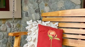 A wooden bench with a ruffled white cushion and a red pillow with a flower design. - Peaceful 2-bedroom, 2 bath  apartment in Boquete with vista to Baru (Boquete)