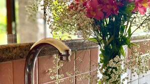 A kitchen sink with a modern faucet, a glass vase with pink flowers and baby's breath, and a tiled backsplash. - Peaceful 2-bedroom, 2 bath  apartment in Boquete with vista to Baru (Boquete)