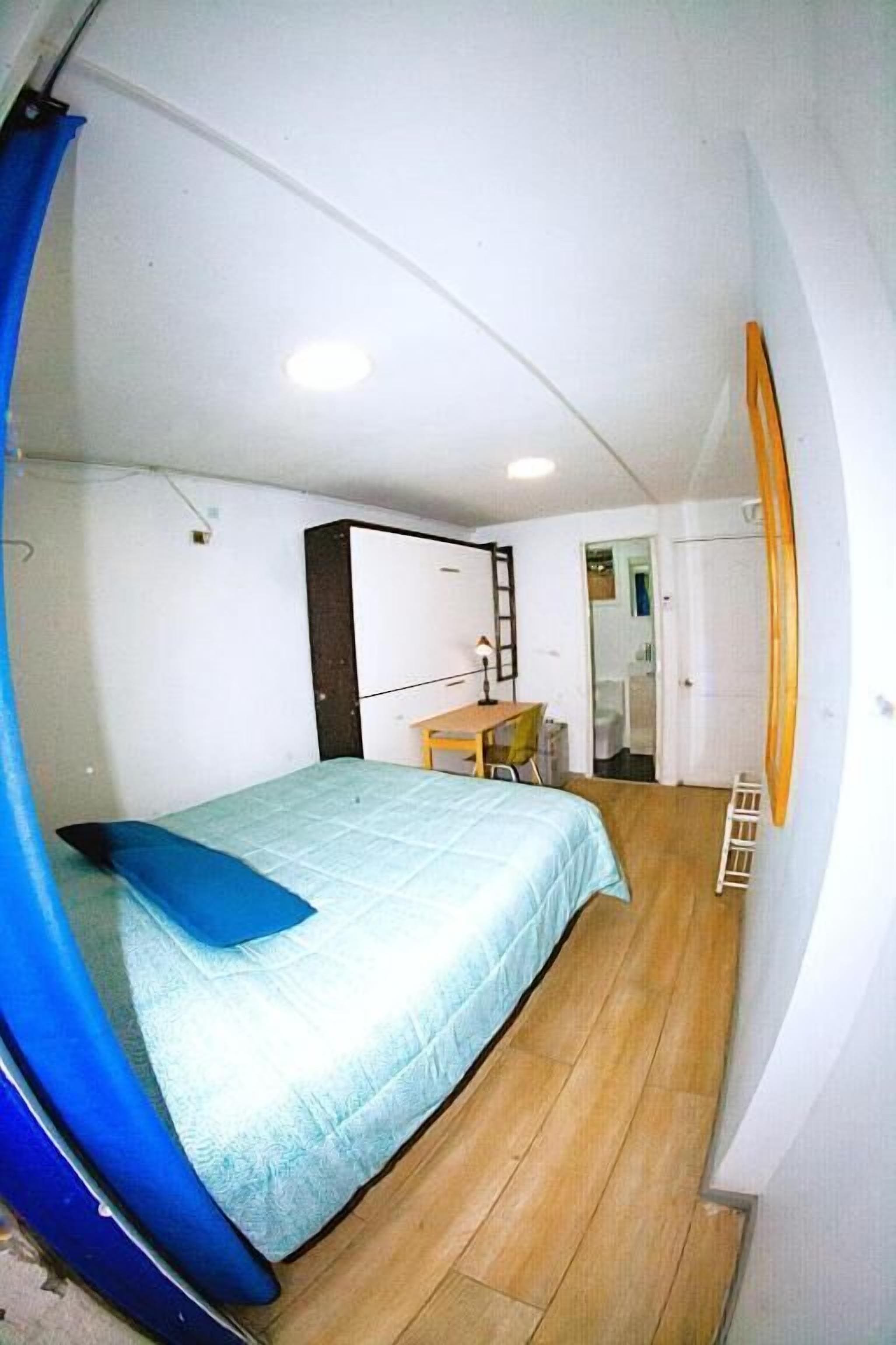 Ein kleines Schlafzimmer mit einem Bett, einem Schreibtisch und einem Kleiderschrank.