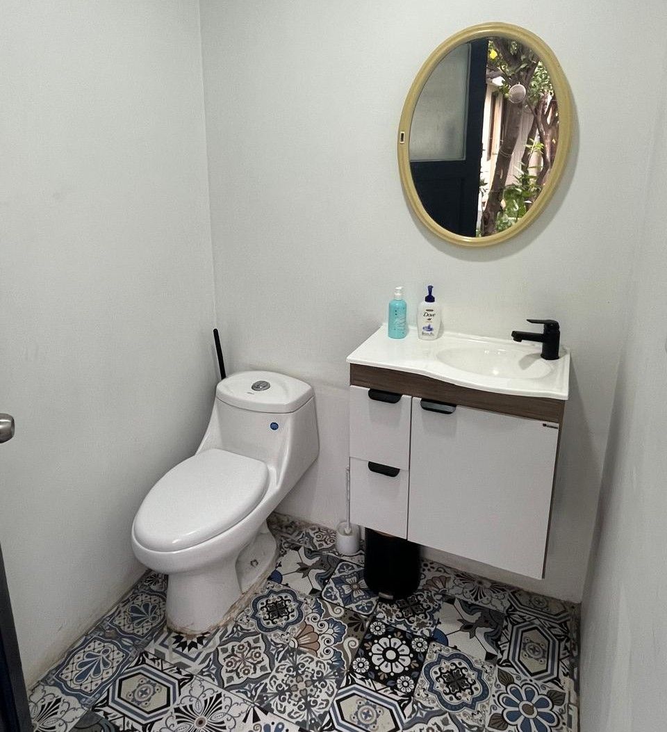 A bathroom with a toilet, a sink, and a mirror.