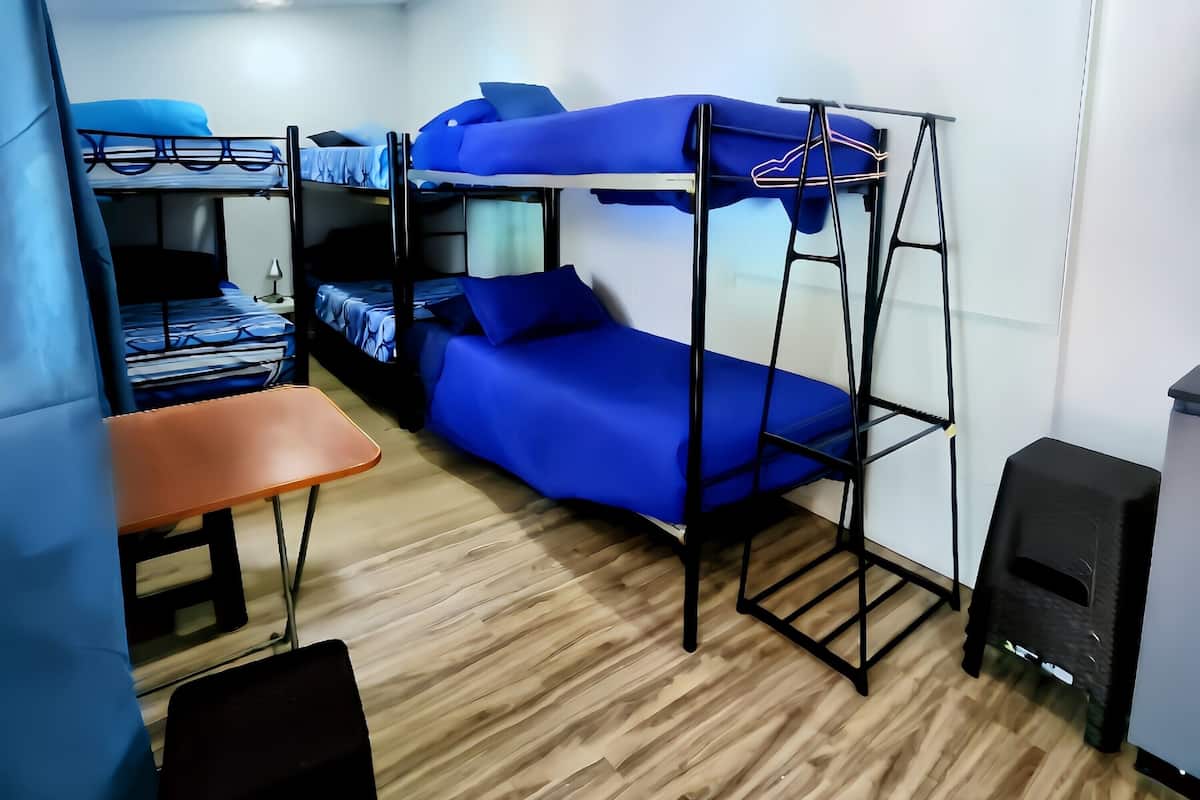 Une chambre de dortoir équipée de lits superposés, d’un bureau, d’une chaise et d’un haut-parleur.