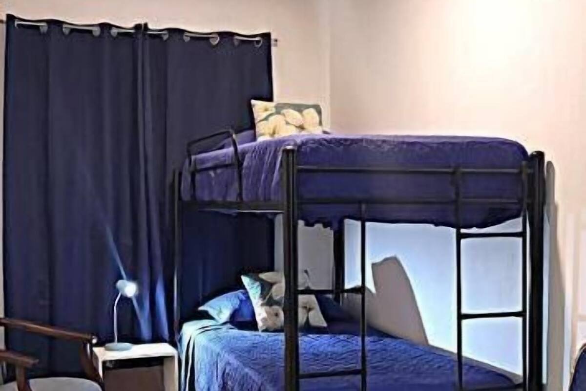 Une chambre avec un lit superposé, une chaise, un bureau et un rideau.