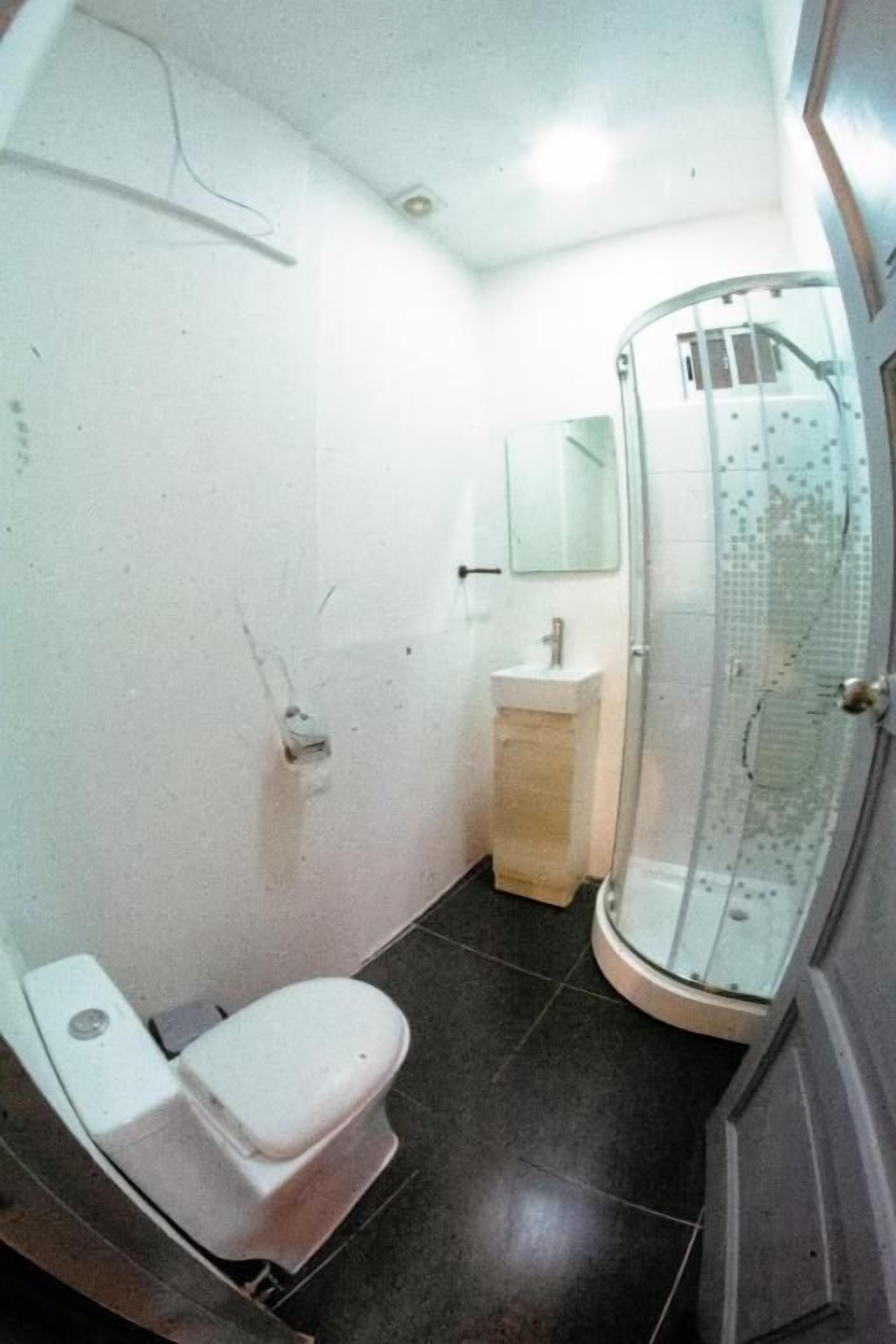 A compact bathroom with a toilet, sink, and glass shower enclosure.