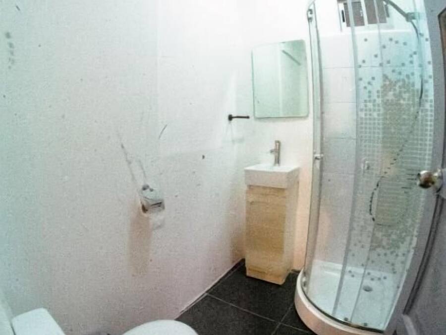 A compact bathroom with a toilet, sink, and glass shower enclosure.