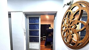 Un couloir au plancher de bois mène à une pièce où se trouvent un lit et un mur bleu.