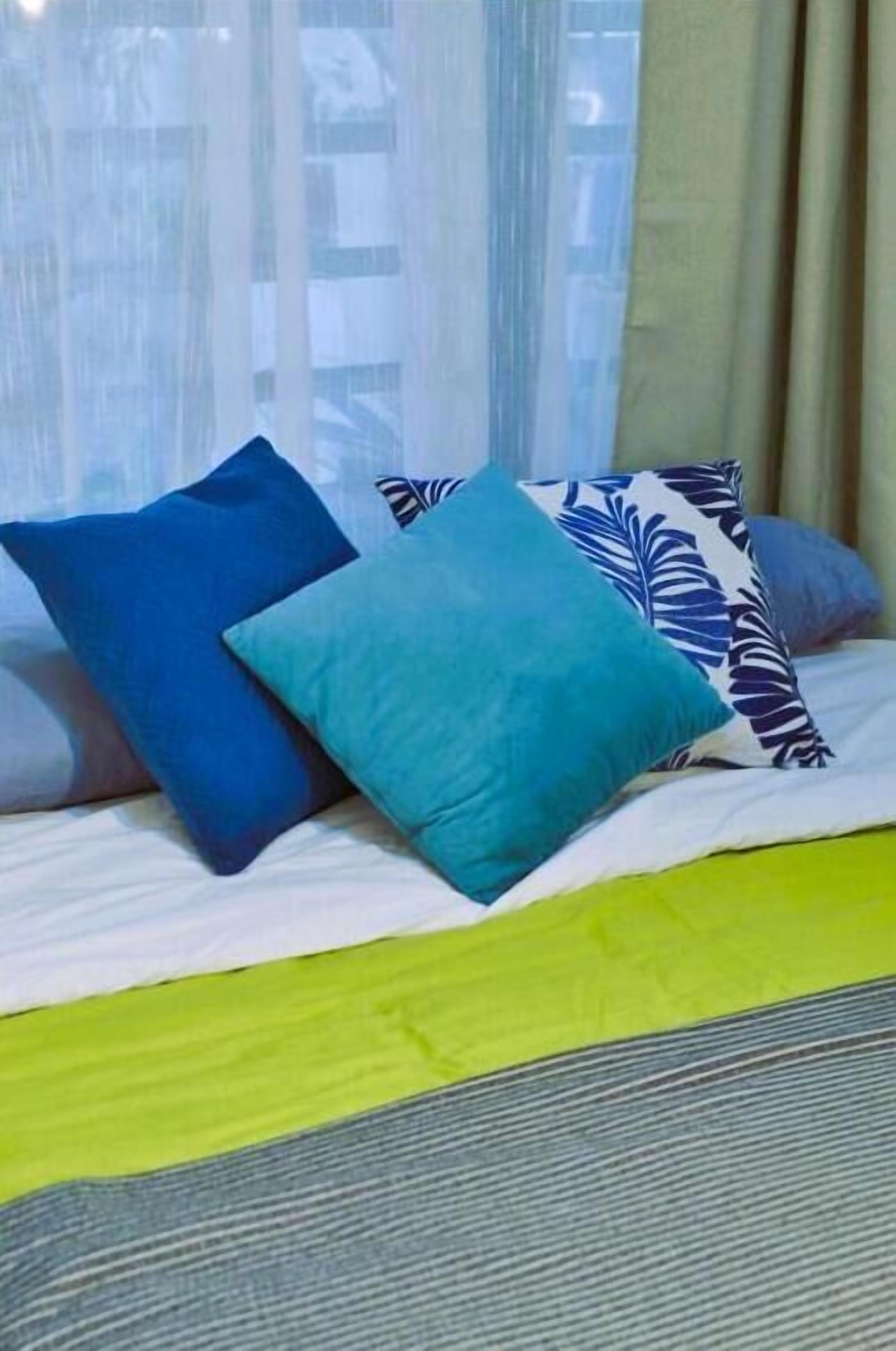 A bed with a green bedspread, two pillows, and a striped blanket.