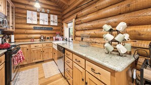 Eine Holzhütte-Küche mit Granit Arbeitsplatte, Holzschränken und einem Becherhalter.