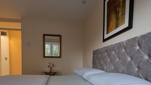 Una cama bien hecha con ropa de cama a rayas, un cabecero capitonado y un cuadro en la pared.
