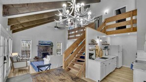 A spacious loft with a wooden staircase, a kitchen with white cabinets, and a large chandelier. - Walk to Slopes-Mountain Views-Firepit-Sleeps 10 (Beech Mountain)