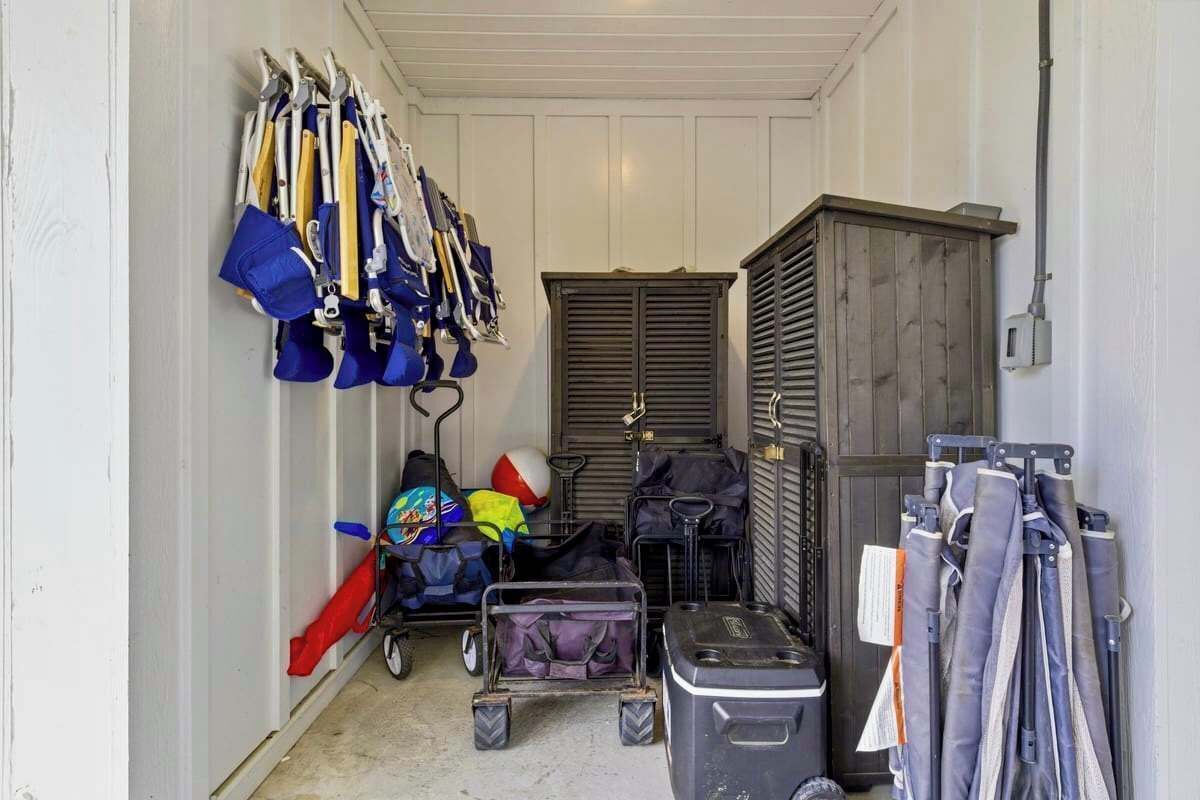 Een smalle gang met aan de linkerkant een rij bagagerekken, een kar met tassen in het midden en een gesloten deur aan de rechterkant.