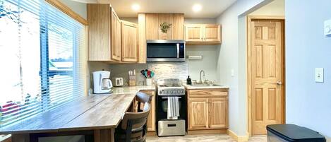 A compact kitchen with wooden cabinets, a microwave, a toaster, and a sink.