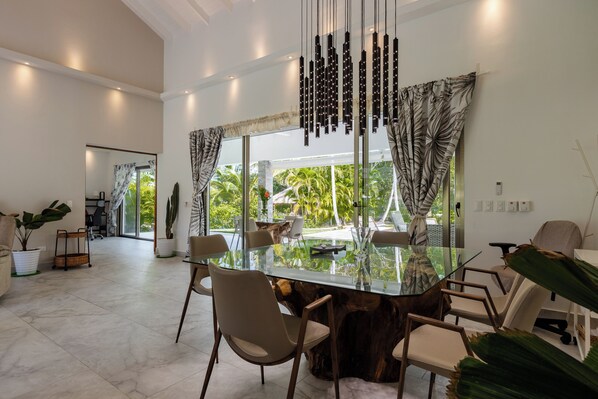 A modern dining area with a glass table, wooden chairs, and a view of the outdoors.