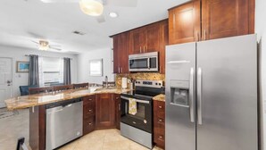 Una cocina moderna con armarios de madera oscura, electrodomésticos de acero inoxidable y encimera de granito.