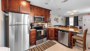A compact kitchen with stainless steel appliances, wooden cabinets, and a central island. - 3 Min Walk to Beach | Modern Coastal Retreat (Indian Rocks Beach)