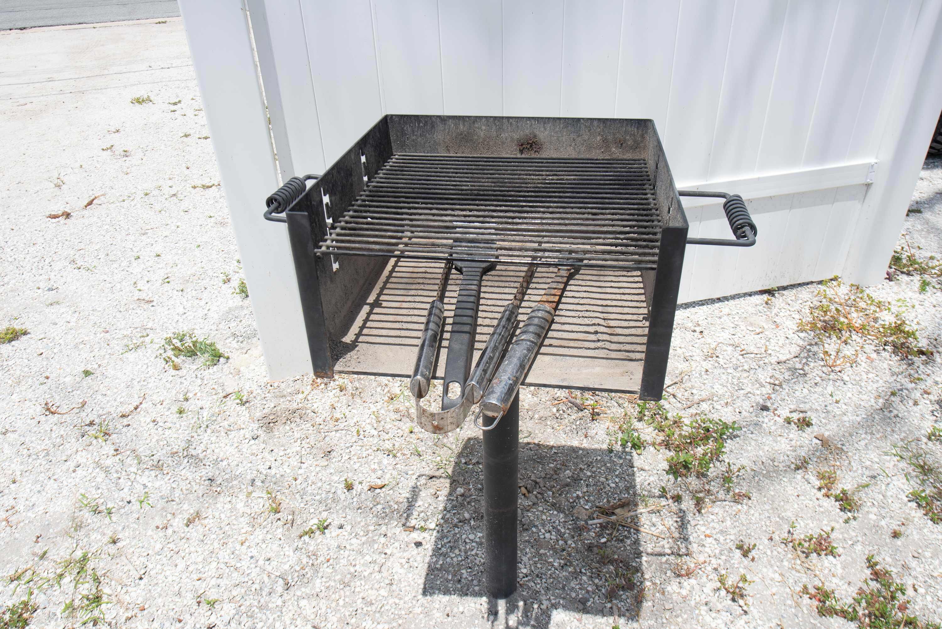 Un barbecue portable doté d’une grille en métal, d’une poignée et d’un support.